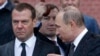 Russia -- Russian President Vladimir Putin (R) speaks with Prime Minister Dmitry Medvedev in the rain during a wreath-laying ceremony marking the anniversary of the Nazi German invasion in 1941, by the Kremlin wall in Moscow, June 22, 2017