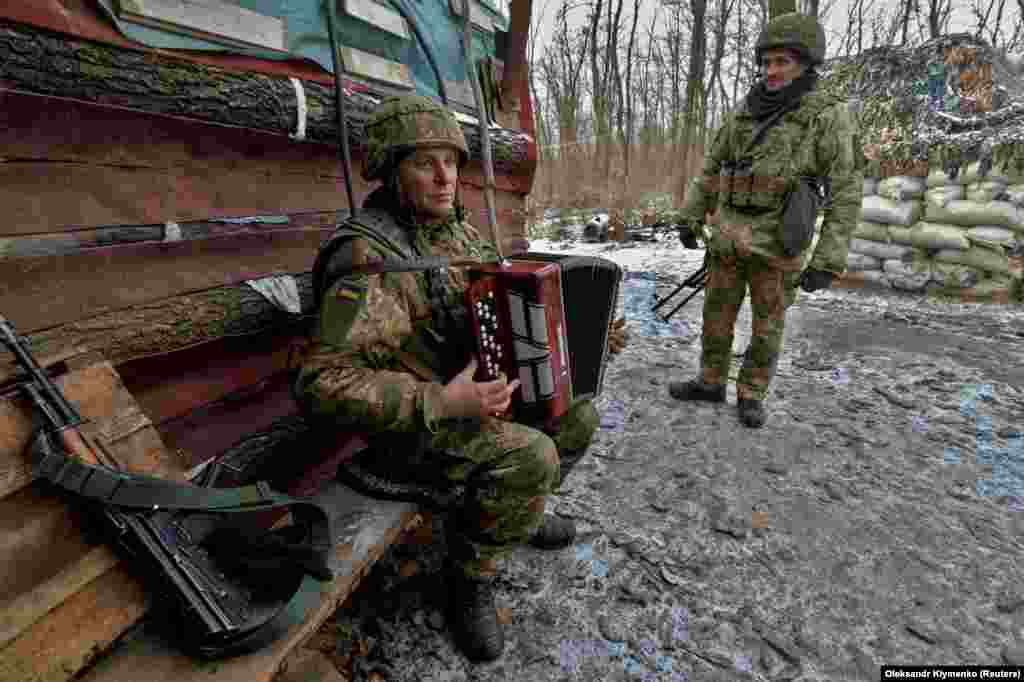 Украинский военнослужащий играет музыку на линии соприкосновения с поддерживаемыми Россией боевиками в Донецкой области на востоке Украины